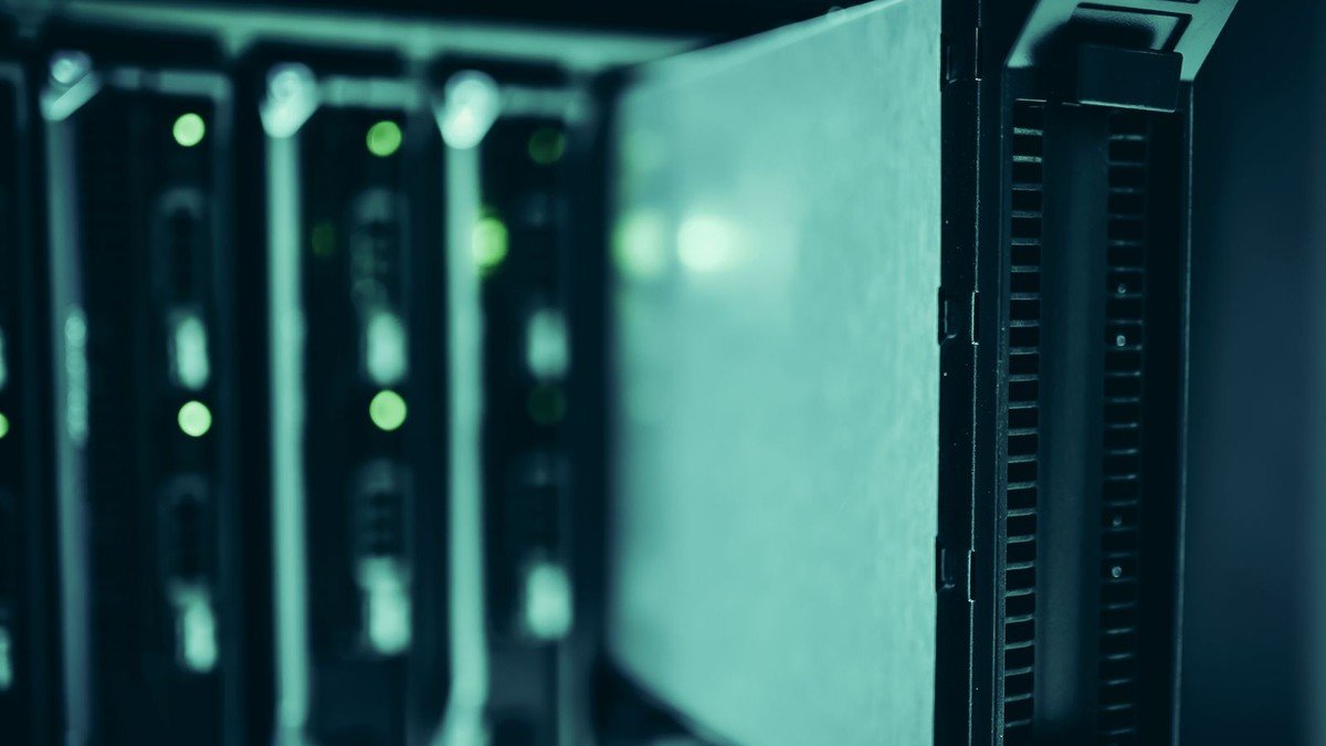 Server racks in a data center with green status lights — the inference infrastructure behind AI agent costs